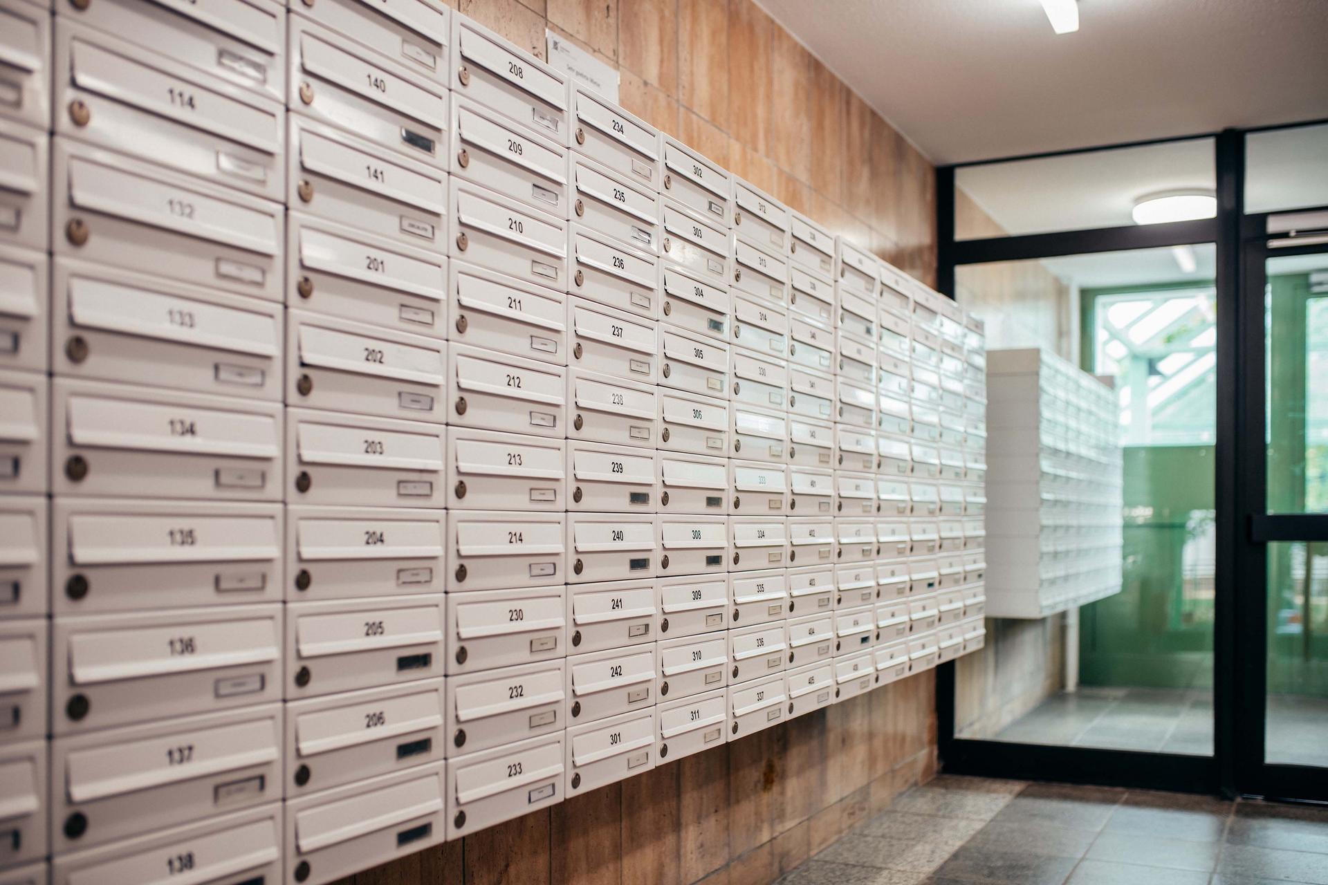 Zahlreiche weiße Briefkästen, die über die gesamte Wand angebracht sind